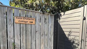 A wooden fence with a sign that reads 'Cute Character Cottage.'