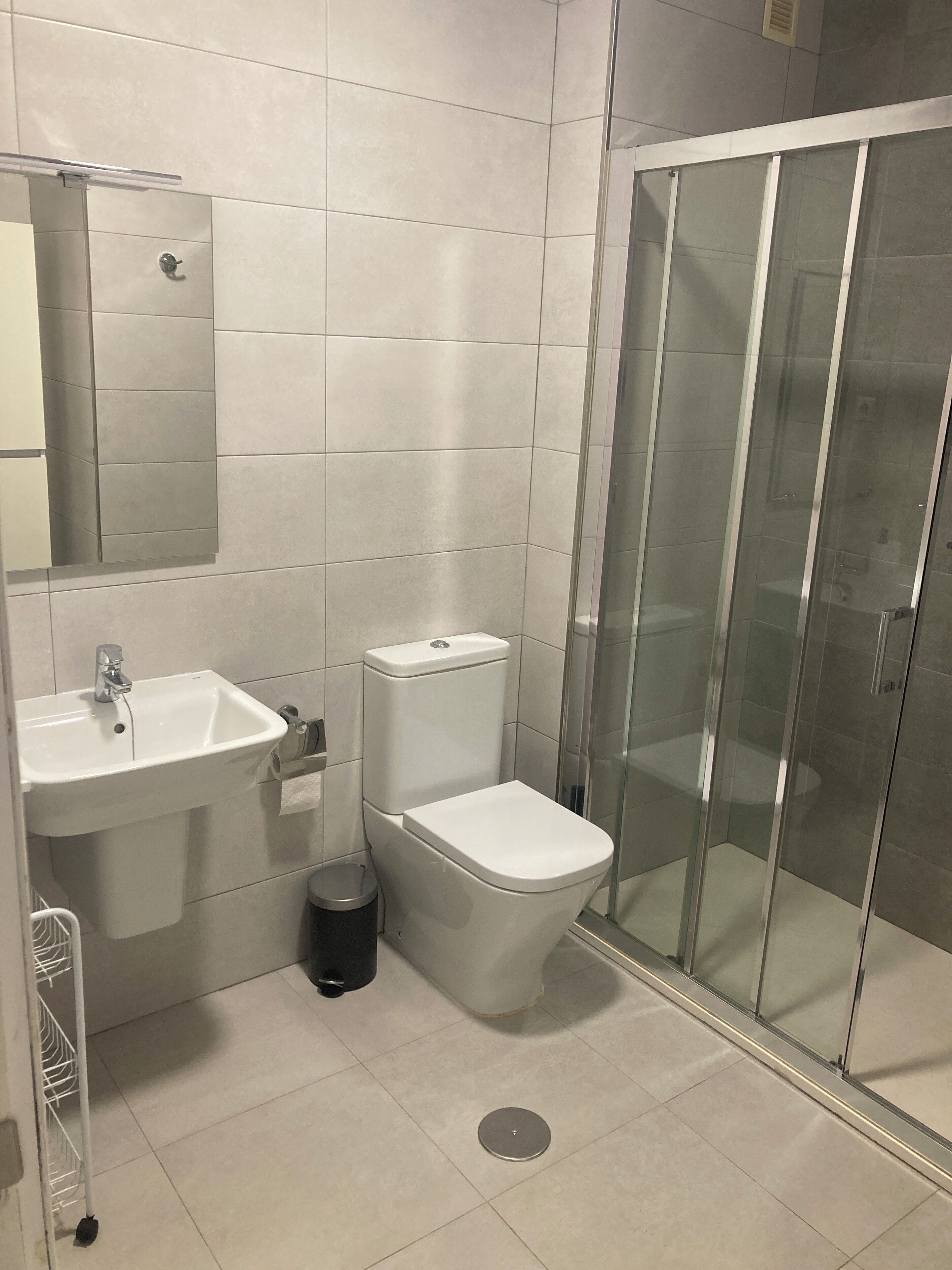 Moderni kylpyhuone, jossa on pesuallas, wc ja lasiseinällä varustettu suihku.