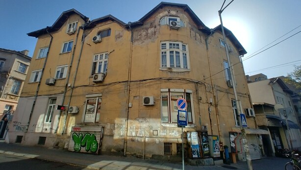 Un immeuble à plusieurs étages, doté d’une façade jaune, de nombreuses fenêtres et de climatiseurs.