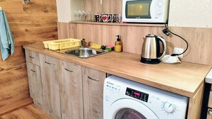 Une cuisine compacte équipée d’un lave-linge, d’un four à micro-ondes et d’un évier.