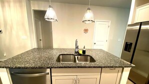 A kitchen with granite countertops, stainless steel sink, white cabinets, and a stainless steel refrigerator. - Charming 3-bedroom villa with WiFi and AC in marvelous Raleigh (Raleigh)