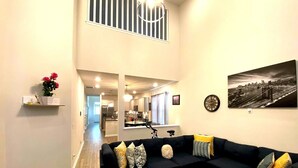 A modern living room with a sectional sofa, a dining area, and a kitchen in the background. - Charming 3-bedroom villa with WiFi and AC in marvelous Raleigh (Raleigh)
