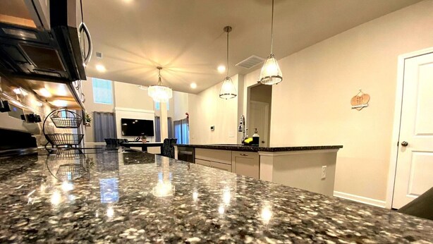 A kitchen with a granite countertop, pendant lighting, and a large island. - Charming 3-bedroom villa with WiFi and AC in marvelous Raleigh (Raleigh)
