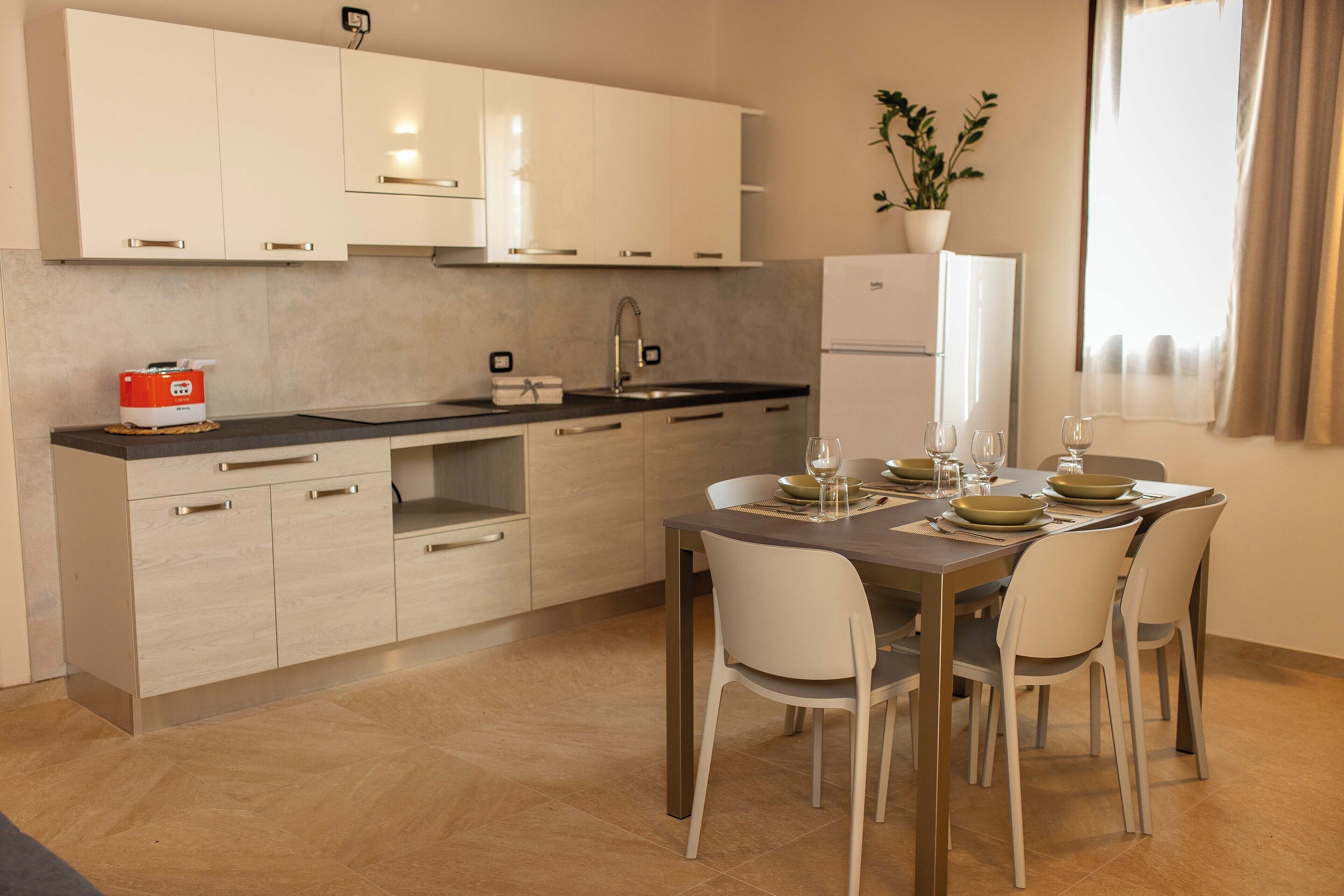 A modern kitchen with white cabinets, a black countertop, and a dining area with a table set for four.