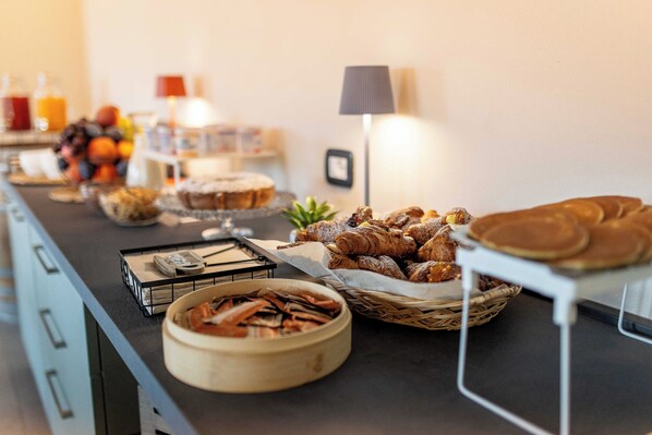 A buffet table with various food items including fruits, pastries, and beverages.