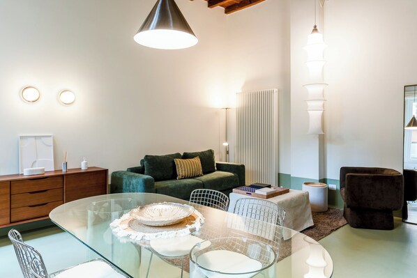 Una sala moderna con una mesa de comedor de vidrio, un sofá verde y un sillón negro.