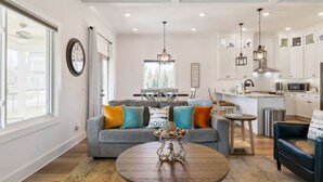 A modern living room with a grey sofa, a wooden coffee table, and a kitchen in the background. - Barefoot Breeze w/Pool, Kayaks, Fireplace (Winchester)