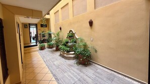 A corridor with tiled flooring, potted plants, and a staircase leading to an upper level. - AMANÁA Hotel Boutique (Playa del Carmen)