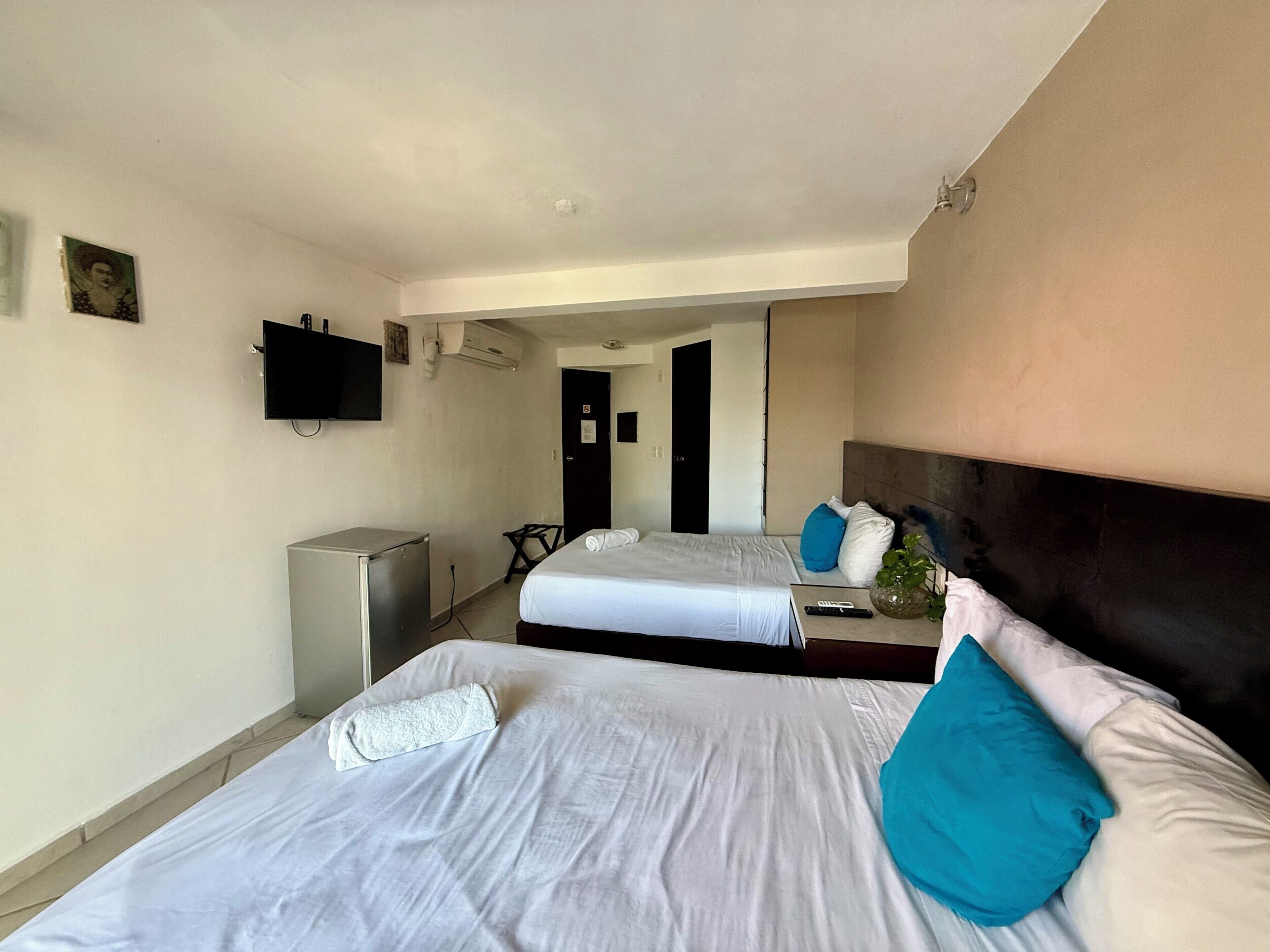 Hotellihuone, jossa on kaksi sänkyä, televisio, työpöytä ja tuoli.