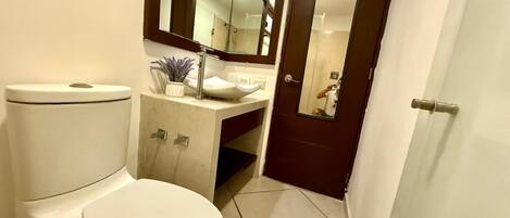 A compact bathroom with a toilet, sink, and mirror.
