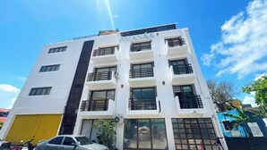 A multi-story building with balconies, large windows, and a yellow garage door. - AMANÁA Hotel Boutique (Playa del Carmen)