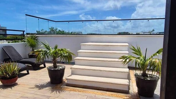 A rooftop terrace with potted plants, a white staircase, and a clear blue sky. - AMANÁA Hotel Boutique (Playa del Carmen)
