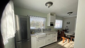 Cocina pequeña con refrigerador, pileta y alacenas. Cuenta con un comedor con mesa y sillas.