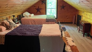 Un dormitorio acogedor en el ático con dos camas, una decoración de estrellas, una radio y una ventana con vistas a árboles.