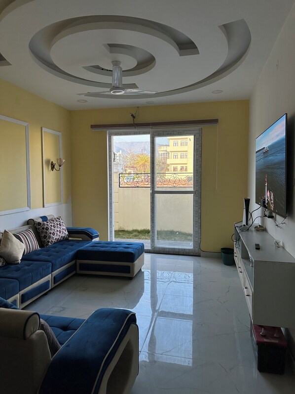 Relax in style with a spacious living area featuring a sofa, flat-screen TV, and sliding glass door to a balcony with a view.