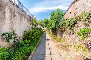 A narrow alleyway flanked by stone walls, with lush greenery and a clear sky. - Guesthouse `Hapa të Lehtë` -  Room 3 - Pro Bono by PikHost (Shkodër)