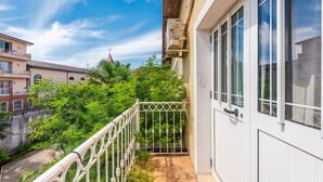 A balcony with a metal railing, a white door, and a view of a church and neighboring buildings. - Guesthouse `Hapa të Lehtë` -  Room 1 - Pro Bono by PikHost (Shkodër)