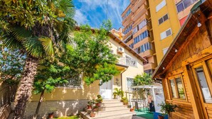 A courtyard with a palm tree, potted plants, and a staircase leading to a building with balconies. - Guesthouse `Hapa të Lehtë` -  Room 1 - Pro Bono by PikHost (Shkodër)
