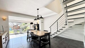 Una cocina moderna con comedor, una escalera y vistas al exterior.
