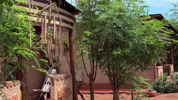 Surrounded by lush greenery, this charming outdoor space features a traditional structure with a sloped roof and wooden pillars.