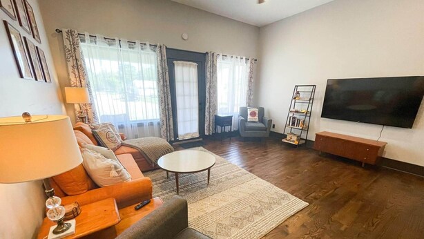 Una sala de estar con sofá, sillón, mesa de centro y televisor sobre un mueble.