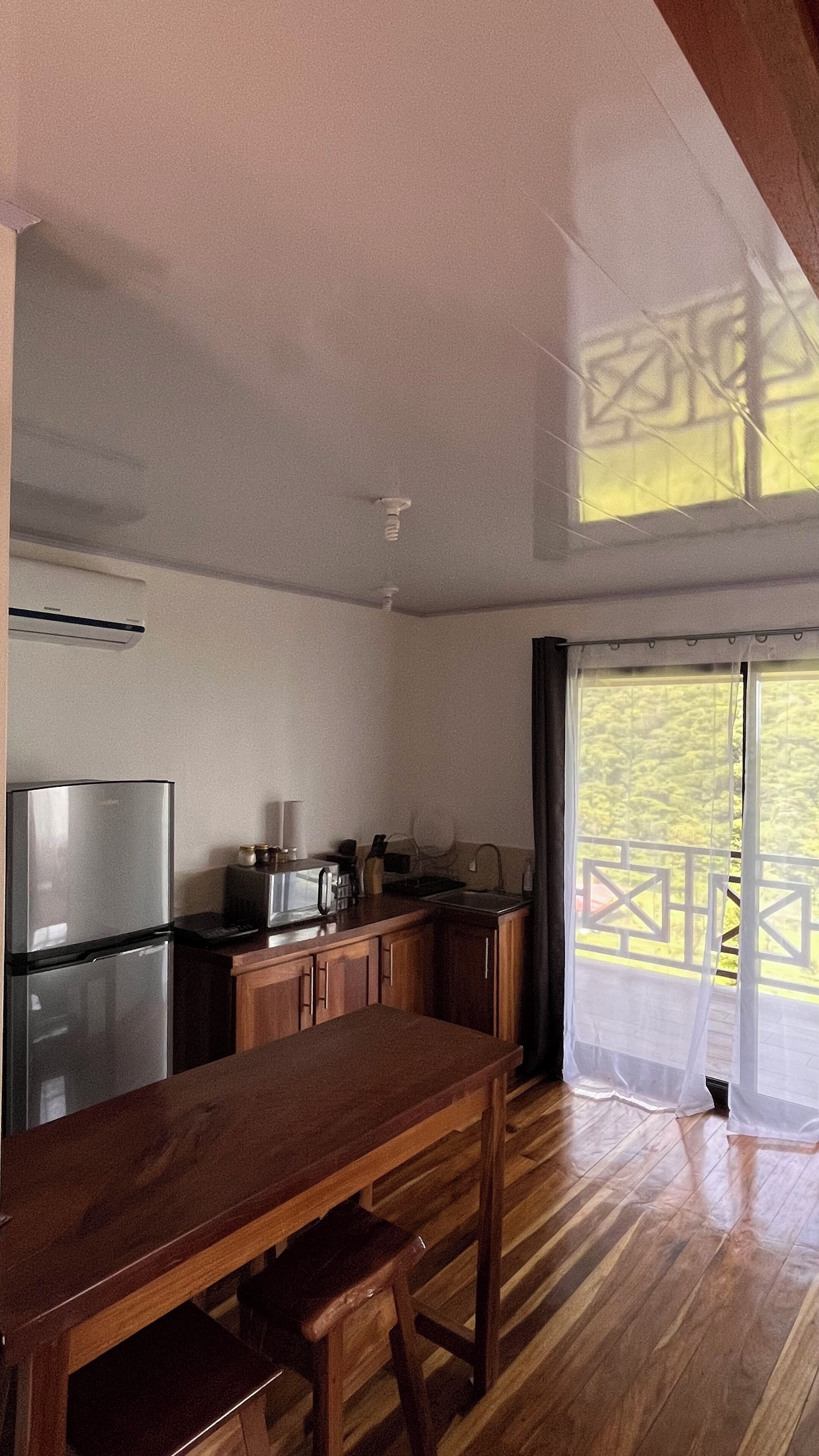 A kitchen with wooden cabinets, a stainless steel refrigerator, and a dining table.