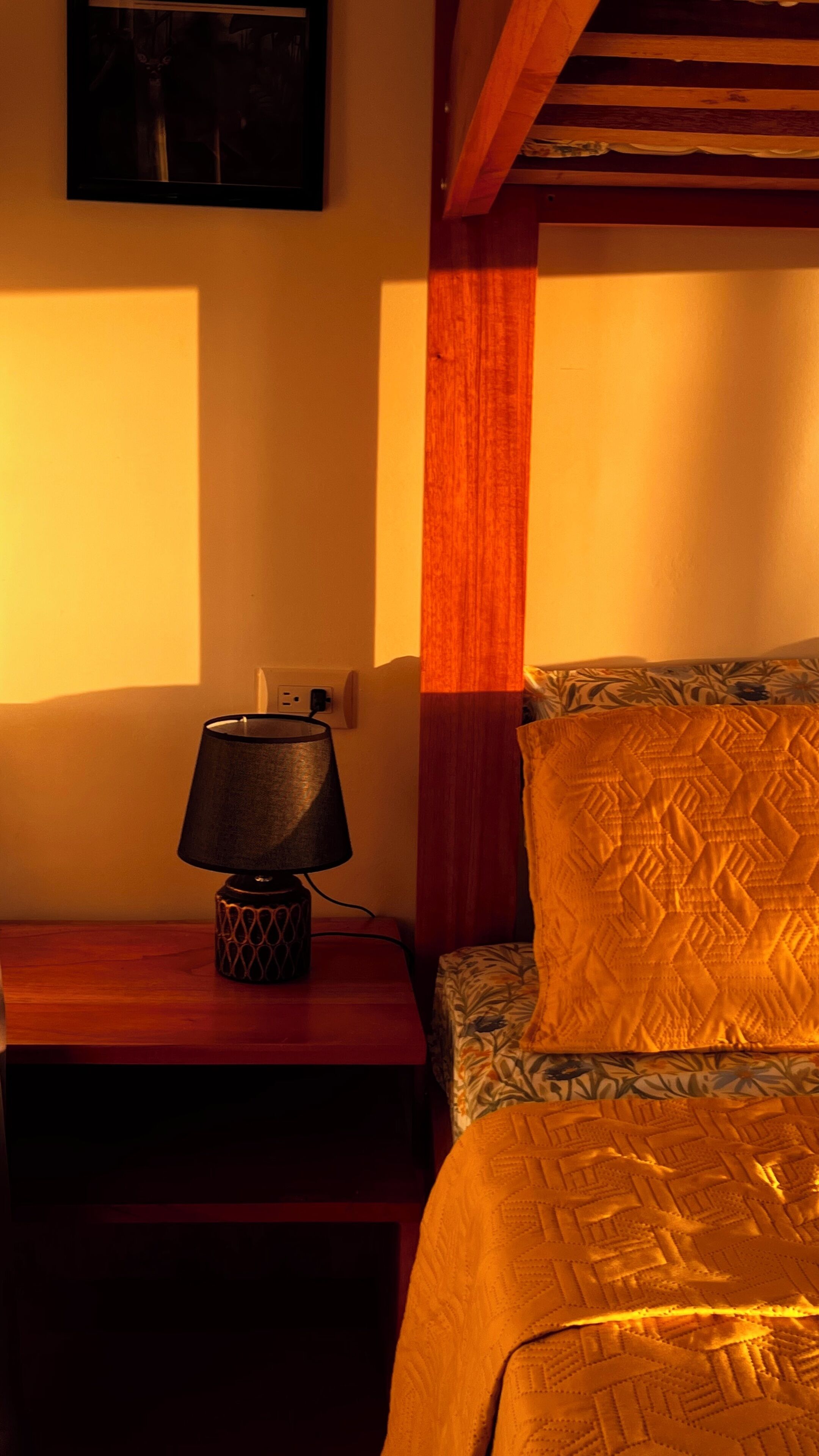 A bedroom with a bed, a nightstand with a lamp, and a wall-mounted TV.