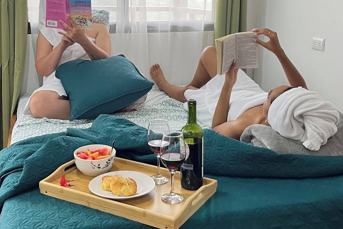 Ein Zimmer mit einem Bett, einem Tablett mit Speisen und Getränken sowie einem Fenster mit Vorhängen.