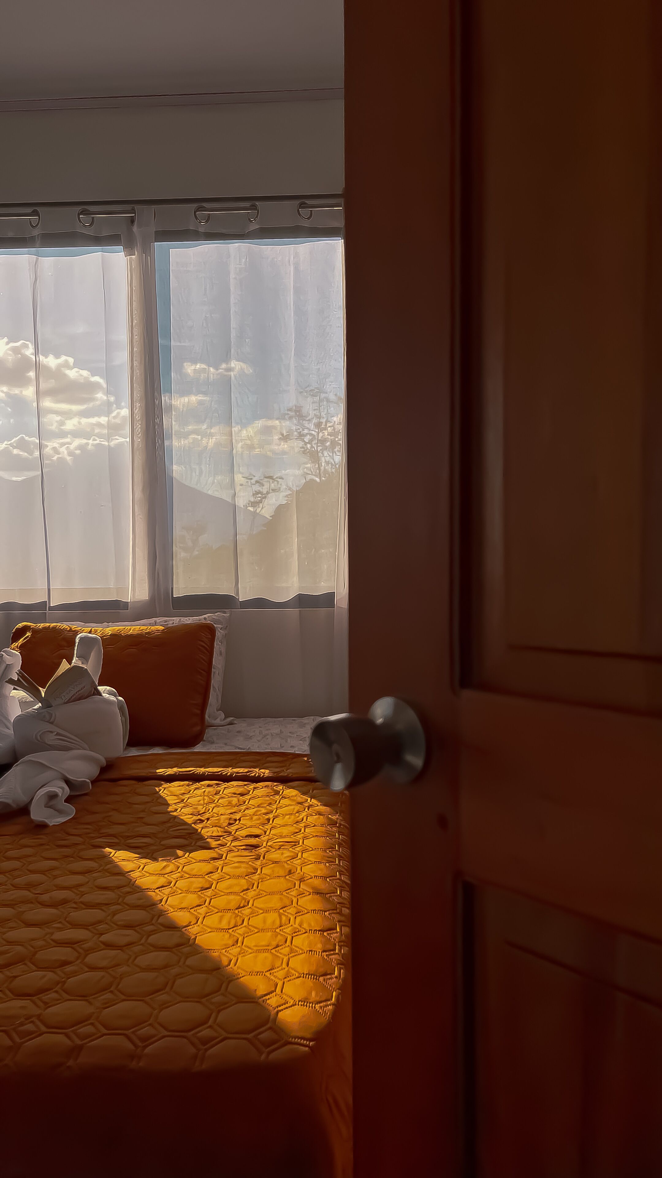 Una habitación de hotel con una cama, una ventana con cortinas y una puerta.