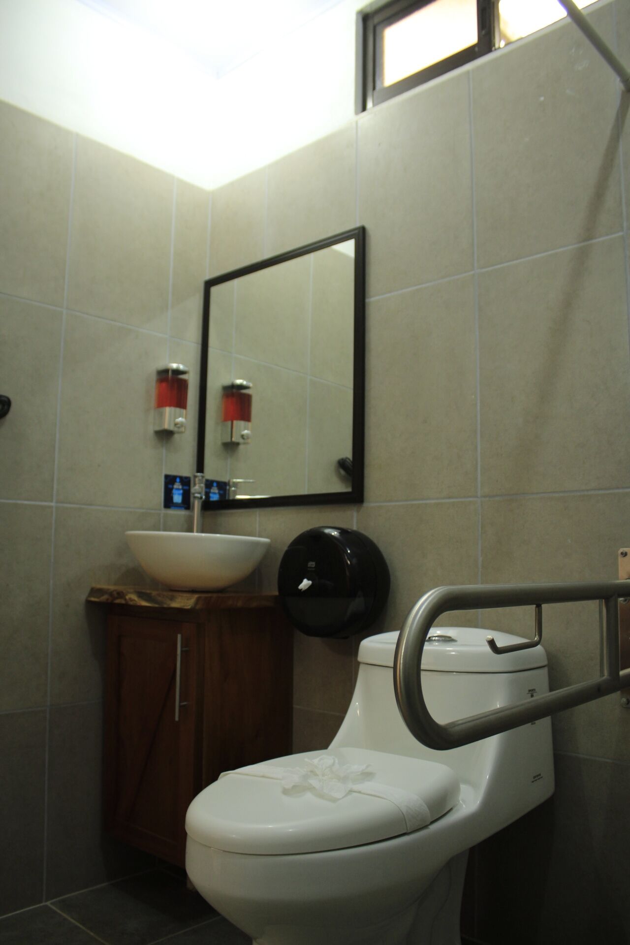 A bathroom with a toilet, a sink, a mirror, and a hand dryer.