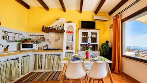 A kitchen with a dining area, a view of the sea, and a balcony with a table and chairs.