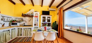 A kitchen with a dining area, a view of the sea, and a balcony with a table and chairs. - Villetta Bonifato with breathtaking views of the Gulf of Castellammare (Alcamo)