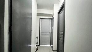 A narrow, tiled hallway with closed doors on both sides, leading to a central door. - Bleu Courant - T4 current view (Mimizan)