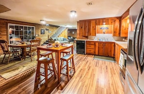 Cozy cabin kitchen with sink, refrigerator, and dining area featuring a wooden table and four chairs.
