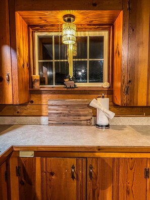 Enjoy a warm kitchen with a chandelier, window view, and decorative elephant figurine.