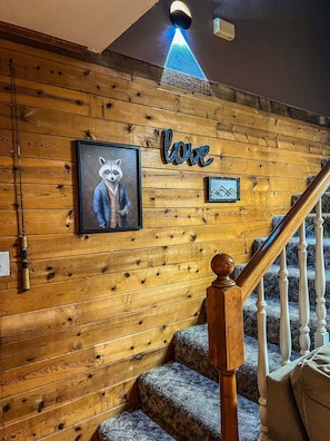 Staircase leads to an upper level with wooden paneling and framed artwork.