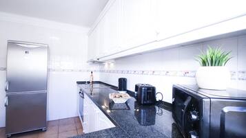 A modern kitchen with a stainless steel refrigerator, a black toaster, and a potted plant.