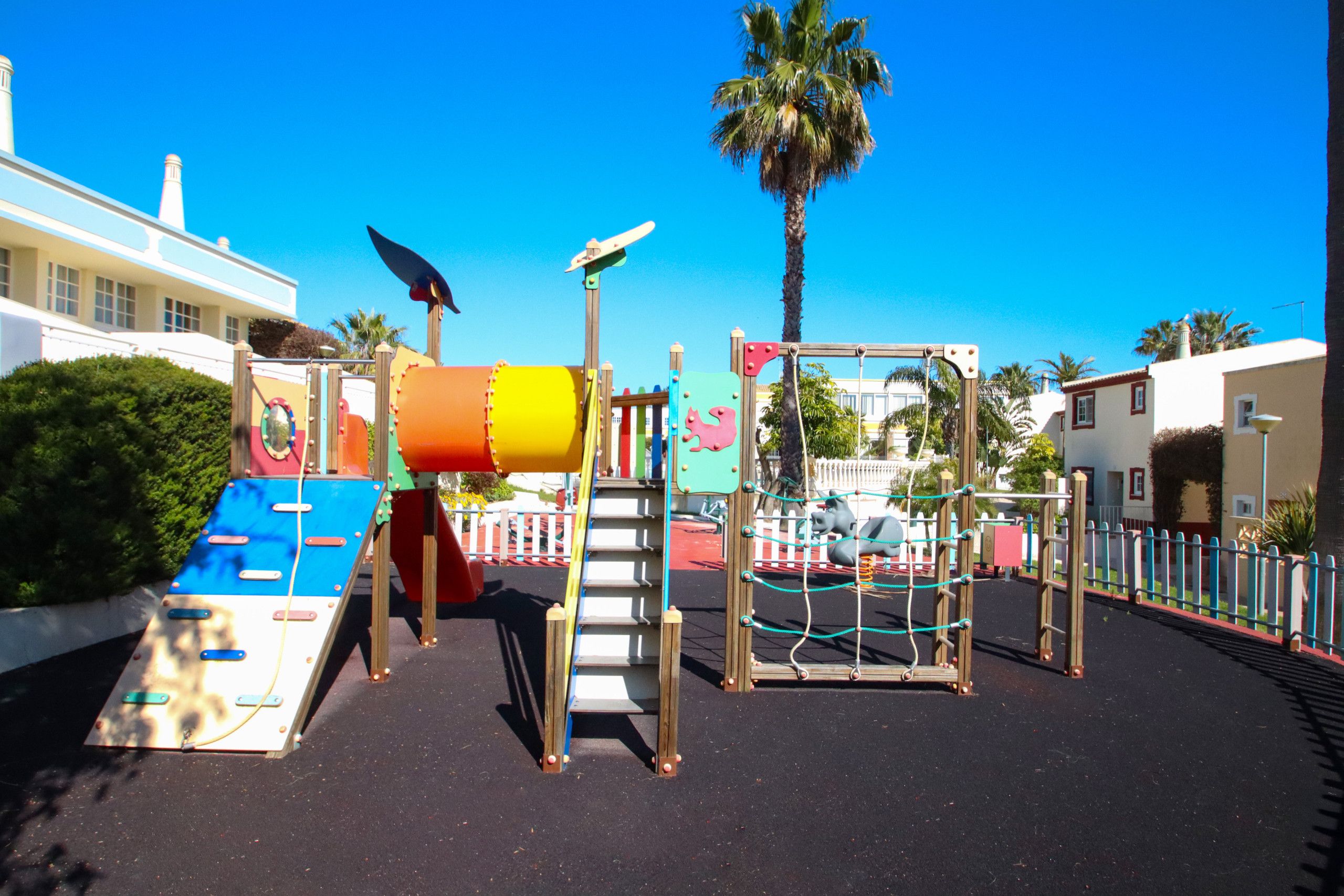 A playground with various play structures, including a slide, climbing wall, and swings.