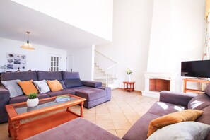 Un salon spacieux comprenant un grand canapé, une table basse et un téléviseur.