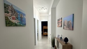A hallway with white walls, a wooden console table, and two framed pictures. - Blue Heracleo Apartment center Trapani (Trapani)