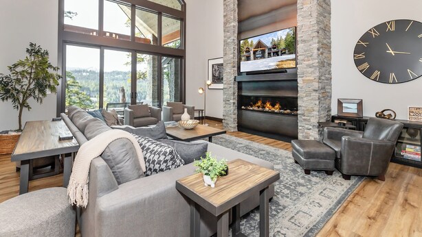 A modern living room with a large fireplace, a stone accent wall, and a large clock. - Sunset View Retreat: Theater & Hot Tub Suncadia (Cle Elum)