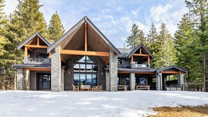 A modern lodge with a stone facade, large windows, and a spacious outdoor seating area. - Sunset View Retreat: Theater & Hot Tub Suncadia (Cle Elum)