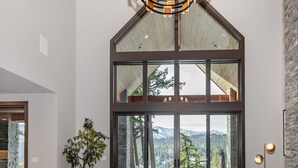 A spacious living room with a large window, a chandelier, and a cozy seating area. - Sunset View Retreat: Theater & Hot Tub Suncadia (Cle Elum)