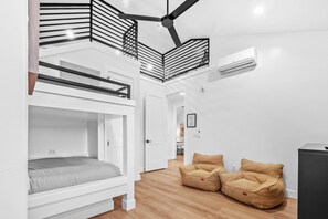 Ein modernes, mehrgeschossiges Schlafzimmer mit Stockbetten, einer Treppe und einer Sitzecke mit Sitzsäcken.