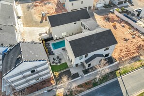 A multi-story residential building with a swimming pool, a covered patio, and a construction site nearby.