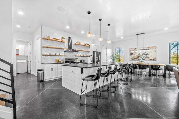A modern kitchen with white cabinetry, a central island, and bar stools.