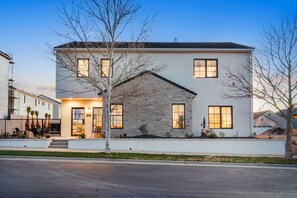 A modern two-story house with a stone facade, large windows, and a well-lit entrance.