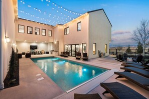 A modern outdoor pool area with lounge chairs and a dining setup.