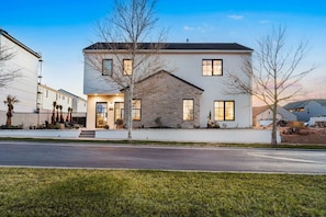 A modern two-story house with a stone facade, large windows, and a well-maintained lawn.