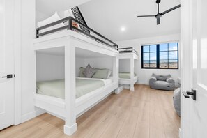 A room with bunk beds, a gray sofa, and a large window with a view.
